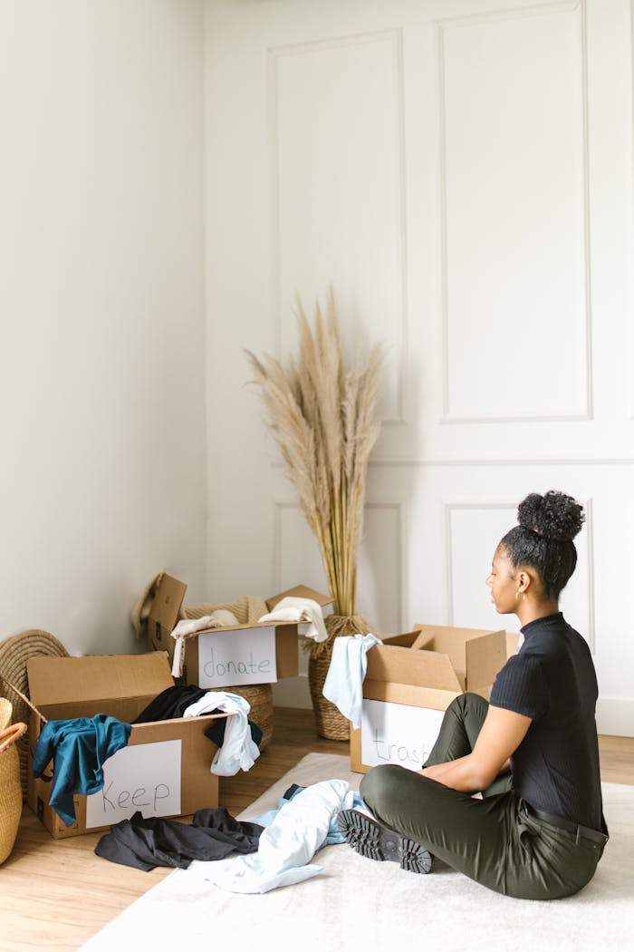 Home A woman sorts clothes into labeled boxes for donation in a bright room.